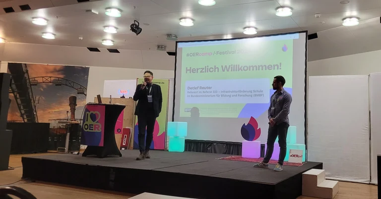 Foto: OERcamp Eröffnung, Detlef Reuter (BMBF, links), Frank Homp (OERcamp Organisator, rechts)