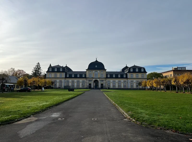 Eine Wissenschaftlerin und ein Wissenschaftler arbeiten hinter einer Glasfassade und mischen Chemikalien mit Großgeräten.