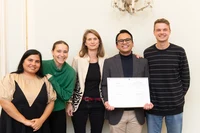 Yohanes holds the DAAD Prize award certificate with her supervisor Prof. Leonie Esters and his working group and office mates.