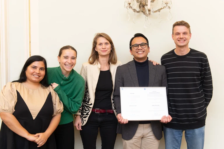Yohanes holds the DAAD Prize award certificate with her supervisor Prof. Leonie Esters and his working group and office mates.